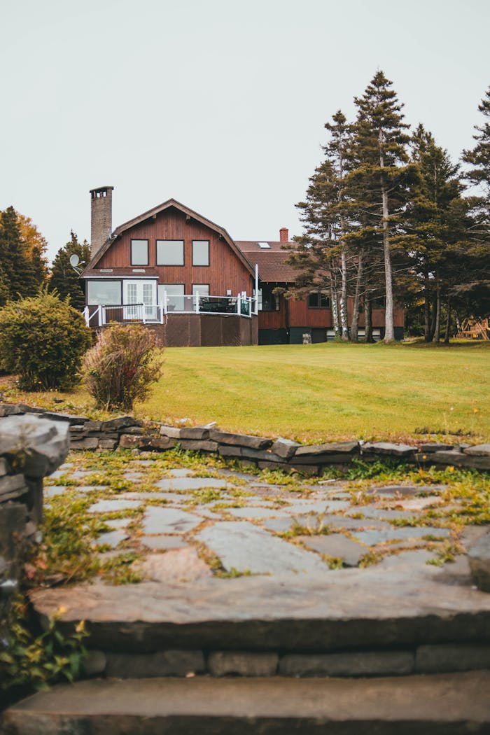 Picturesque rustic house surrounded by trees and stone pathways, perfect for serene getaways.